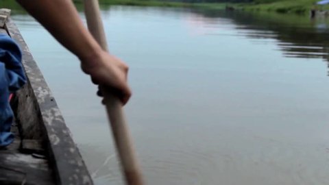 Close up of a paddle rowing upstream the Amazon river, on a traditional wood canoe.