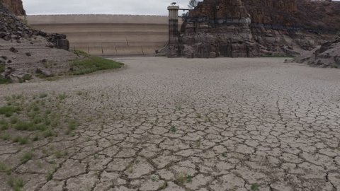 4K aerial tilt up view from the floor to the top of the dam wall that has dried up due to a drought from climate change and global warming