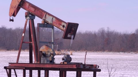 Abandoned Ark Oil Pumps left in an open, frozen field. Camera tracks and zooms at the same time.