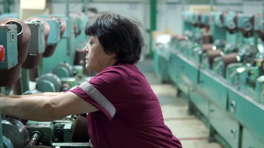 Female worker of a textile factory running on the machine, and installs and removes the spool of thread | Shutterstock HD Video #1025492063