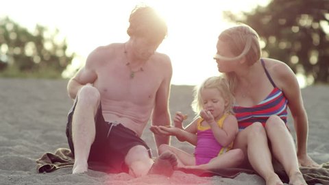A family sits on the beach and has a snack