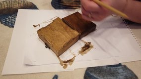 Woman painting wooden box with a brush in brown color