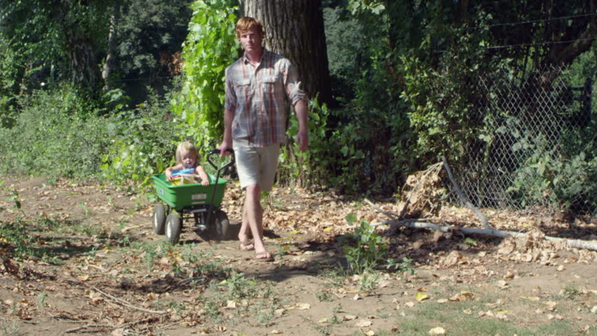 A father pulls his toddler in a plastic wagon