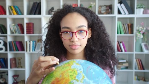 Young beautiful african american woman choosing the vacation route, hanging globe in her hands