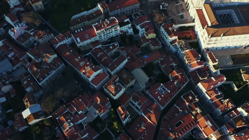 Aerial; drone top down view of old city roofs; evening in Portugal capital, sunlights and dusk shadows on ancient houses; beautiful cityscape with historical touristic routes and sunset sky; camera up | Shutterstock HD Video #1025513288