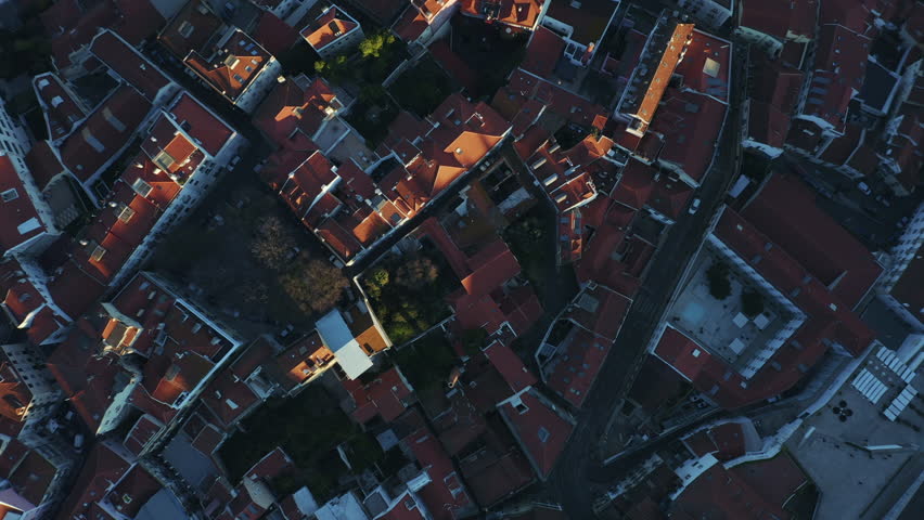 Aerial top down view; Lisbon landmark with tiny houses, moorish architectural elements; drone flight over picturesque labyrinth of narrow streets small square, evening time Portugal, camera moves away | Shutterstock HD Video #1025513309