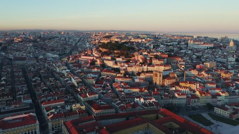 Aerial view; drone flight forward to the ancient building with brown rooftops; sunset time in Lisbon; beautiful winter evening in Portuguese capital; Alfama oldest historic district; view from above