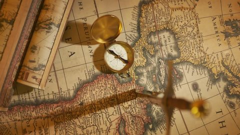 Close-up on the old vintage compass lying on the ancient map. An old-fashioned instrument was used in sailing for navigational purposes at the age of great geographical discoveries.
