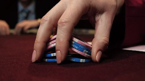 Casino: dealer shuffles the poker chips and performing trick with chips use one hand. Hand close-up.