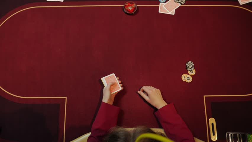 Casino dealer putting cards on red table, poker game, gambling, close-up hands. Top view.