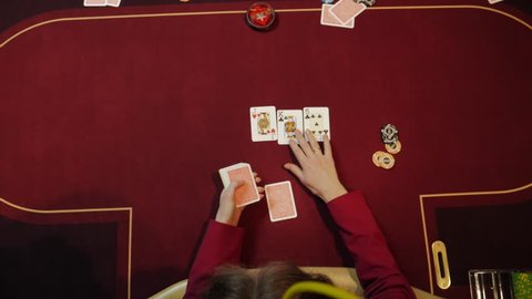 Casino dealer putting cards on red table, poker game, gambling, close-up hands. Top view.