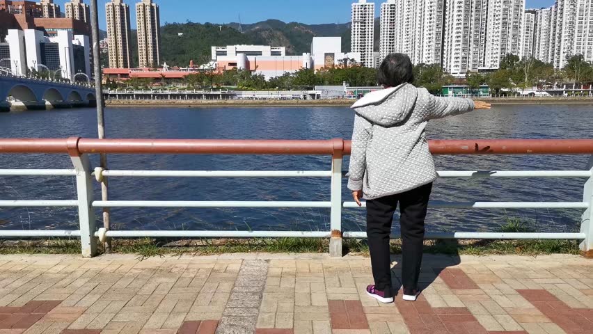 Retired woman doing exercise in front of the Sha Tin Shing Mun River at Hong Kong