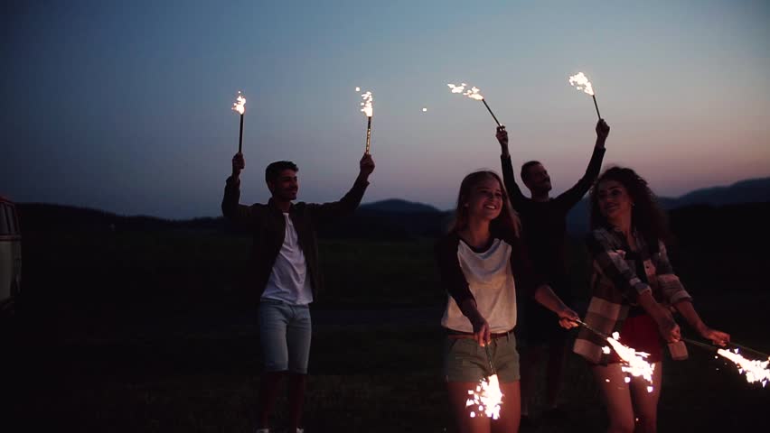 A group of friends with sparklers standing outdoors at dusk. Slow motion. | Shutterstock HD Video #1025537204