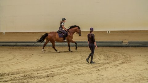This young girl is galloping in a circle in a horse arena.