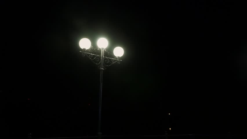 Triple street lamp is lit at night.