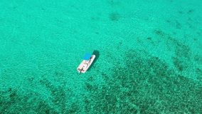 Drone flying over boat in blue green waters in Cayman Islands