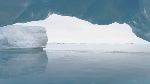 Iceberg Arch Antarctica Ocean Glacier Seascape. Hole in Massive Iceberg Floating in Arctic Blue Water Sea at Greenland. Double Crystal Cave Bridge at North Landscape Shot Footage 4K (UHD)
