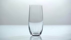 studio shoot of water pouring into transparent glass on white background