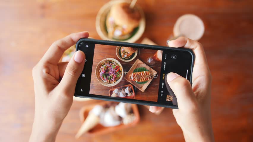 Female Taking Photo of Fast Food Using Mobile Phone in Vegan Restaurant. 4K Slowmotion Flatlay Food Photography on Wooden Table in American Diner. Bali, Indonesia. | Shutterstock HD Video #1025545676