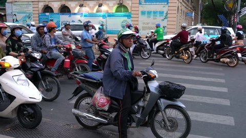 SCOOTERS AND PEOPLE ON THE STREETS OF HO CHI MINH CITY OR SAIGON, VIETNAM – 9 APRIL 2018: Scooters, motorcycles, cars, traffic and people on the streets of Ho Chi Minh City, Vietnam