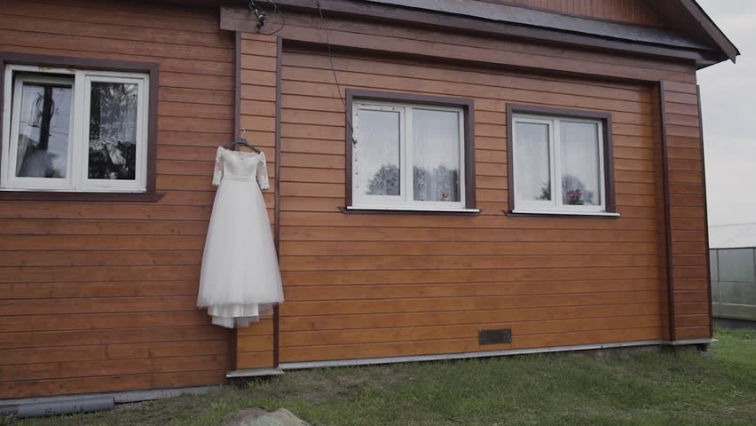 Beautiful wedding dress hanging on a wooden house.