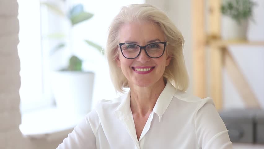 Confident mature middle aged businesswoman in glasses with beautiful face looking at camera posing in office, happy smiling old senior female professional lawyer coach teacher business video portrait | Shutterstock HD Video #1025576921