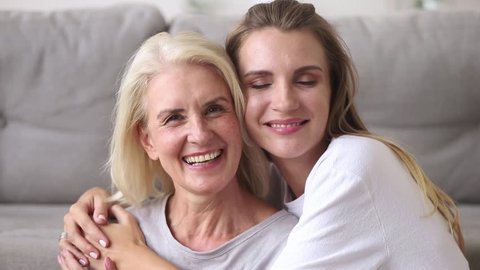 Happy old mature mother embracing young adult woman looking at camera laughing together, smiling senior mom having fun with grown daughter at home enjoy connection and warm relationships at home