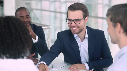 Satisfied caucasian boss hr negotiator talking shake hand of african american candidate partner client making deal, hiring or thanking for collaboration at diverse group business meeting negotiations