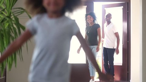 Funny happy cute african american child girl running into new big house exploring moving in, black family real estate mortgage owners tenants entering own home with excited kid having fun in hallway