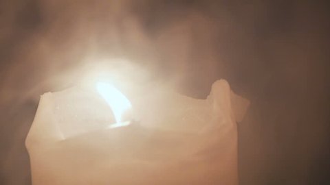A large burning candle is wrapped in white dense smoke.