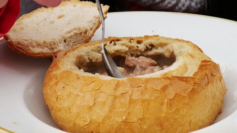 Food concept - Spoon stir soup. Pouring polish traditional soup called zur or white borscht into bread bowl.