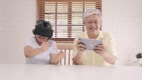 Asian elderly couple using tablet and virtual reality simulator playing games in living room, couple feeling happy using time together lying on table at home. Lifestyle Senior family at home concept. - Powered by Shutterstock - Get 15% off with code: PIKWIZARD15