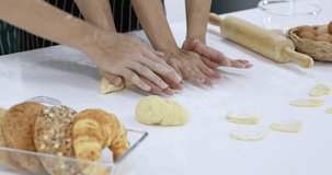 Close up scene video of the hands of two people helped to knead the dough.
