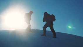 teamwork tourists winter snow business travel trip lends a helping hand. two men with backpacks hiking help each other silhouette lifestyle in mountains with sunlight. slow motion video. rock climbers