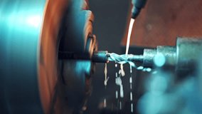 A lathe processes the metal workpiece with coolant which cool the tool and increase the productivity of the process. Close-up. Blurred background.