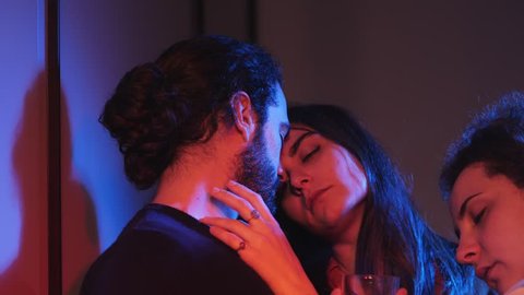 Sensual kiss among two women and man in night club.Polygamy, polyamory
