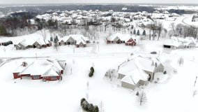 Wealthy suburban neighborhood homes blanketed in deep winter snow, aerial view after blizzard.