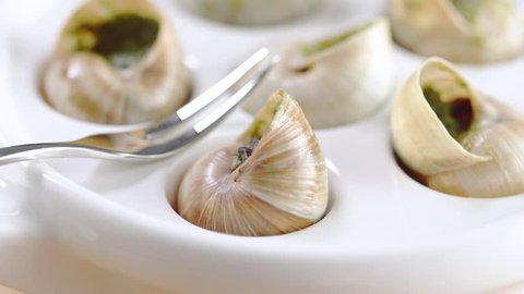 Pouring sauce on a smoothly rotating Escargots (snails)