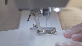 Close-up slow motion video of work of the master seamstress and needle of the automatic sewing machine, good manicure, video camera movement around