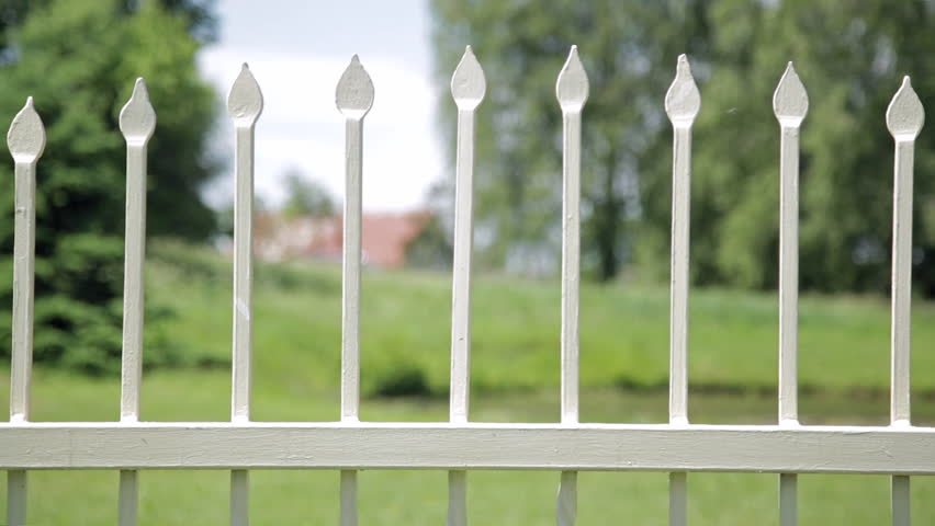 Close up of antique wrought iron fence outdoors in the park. Shallow depth of field, spikes on fence
