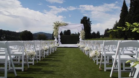 Wedding ceremony arch set up on grass with white chairs against a blue sky with clouds in Portland Oregon 库存视频