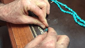 Video showing difficult task of a male re-stringing an expensive turquoise necklace