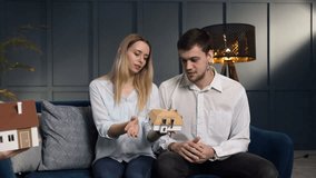 Caucasian young couple choosing model of house with help of female architect in the stylish office.