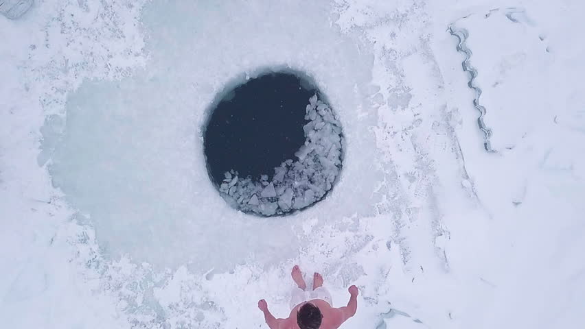 Man jumps into the ice hole. Aerial top down view