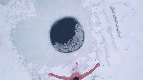 Man jumps into the ice hole. Aerial top down view