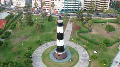 Aerial view of Faro la Marina located in Miraflores's park by the ocean in Lima, Peru. People, tourists and cyclists having fun in "Malecon Costa Verde". Peruvian lifestyle.