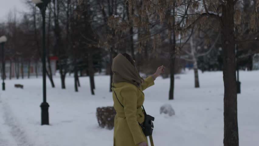 Young Asian girl walks in the park in winter with a selfie stick