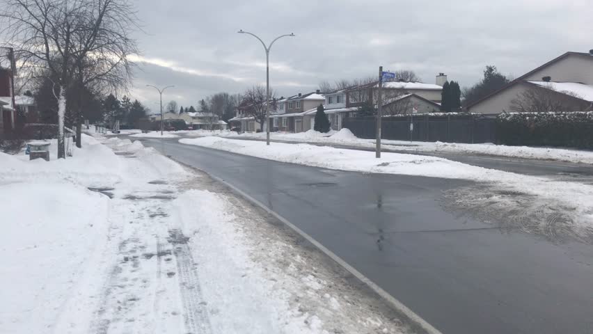 Walking on the sidewalk beside a small town road.