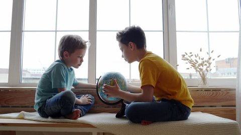 Two boys studying the geography of the earth with a globe
