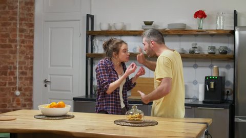 Caucasian couple very emotionally quarreling in kitchen. Relationship difficulties and problems concept